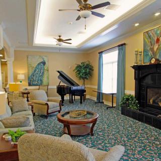 A spacious and elegantly furnished living room with a grand piano, cozy seating area, and a fireplace.