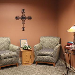A cozy seating area featuring two patterned armchairs, a wooden side table, and warm wall decor.