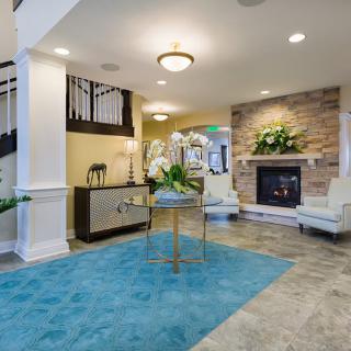 A modern living room with a cozy fireplace, elegant furniture, and a striking blue rug.