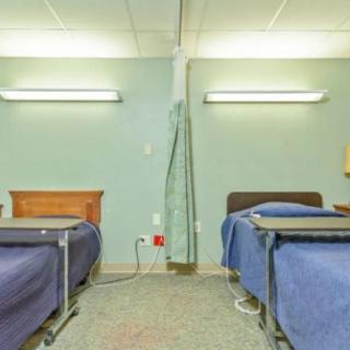 An empty hospital room with two beds separated by a curtain.