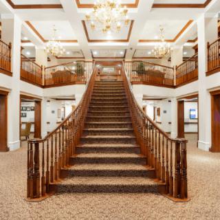 A stunning grand staircase adorned with chandeliers in a luxurious interior setting.