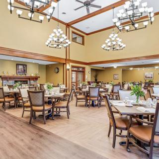 An elegant dining room featuring wooden tables, comfortable chairs, and decorative chandeliers.