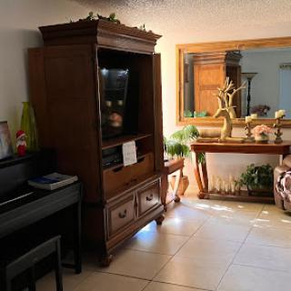 A cozy living room featuring a wooden cabinet, piano, and decorative elements.