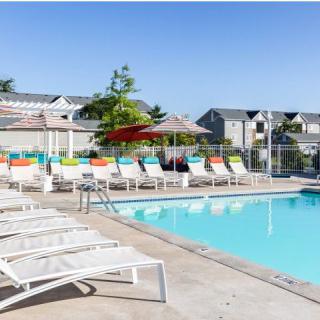 A serene outdoor swimming pool area with colorful sunbeds and umbrellas, perfect for a summer getaway.