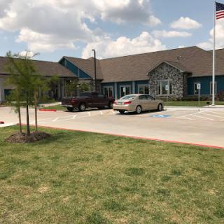 A well-maintained building with a parking lot and an American flag, set against a partly cloudy sky.