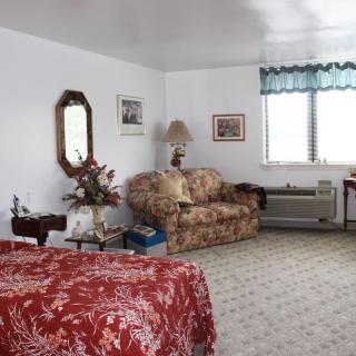 A cozy bedroom with floral-patterned furniture and a window with blue curtains.