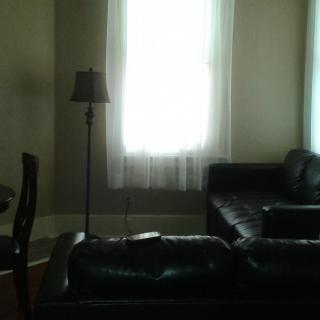 A minimalist living room with a sofa, lamp, and large window.