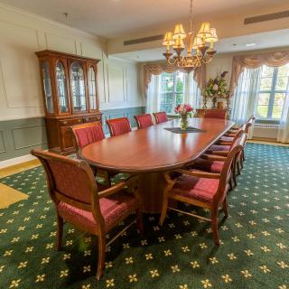 Elegant dining room with a long wooden table, upholstered chairs, and a chandelier.