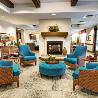 A modern living room interior with blue chairs arranged around a fireplace.