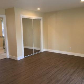 A spacious, empty room with hardwood floors and sliding closet doors.