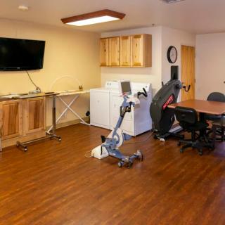 A multi-purpose room featuring an exercise bike, office furniture, and a laundry area with a washing machine and dryer.