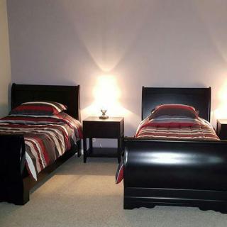 A cozy bedroom featuring two twin beds with striped bedding, positioned on either side of a central nightstand with lamps.
