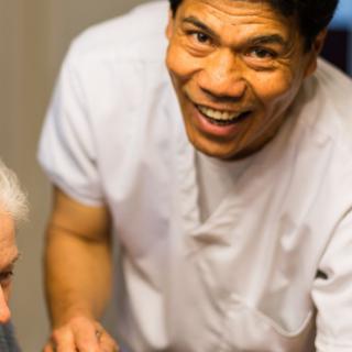 A healthcare professional smiling while assisting a patient.