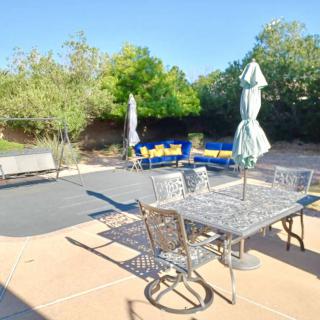 A sunny backyard patio with metal furniture and an umbrella.