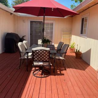 A sunny patio with a dining set under a red umbrella.