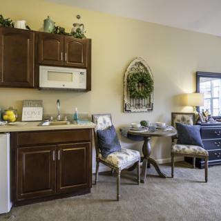 Cozy kitchen and dining area with wooden cabinets, a microwave, and a small round table with two chairs.