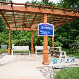 A memorial pergola with benches honoring veterans, set in a tranquil outdoor landscape.