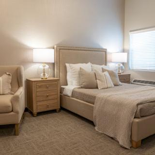A serene and elegantly designed bedroom featuring modern furniture, soft lighting, and neutral tones.