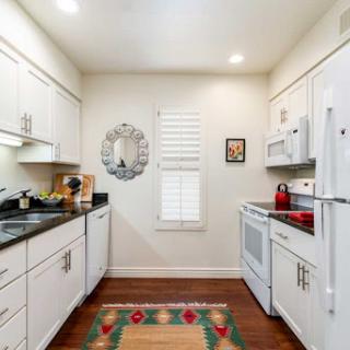 A modern kitchen featuring white cabinetry, black granite countertops, and hardwood flooring.