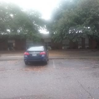 A parked car in a rainy urban setting, partially obscured by fog.