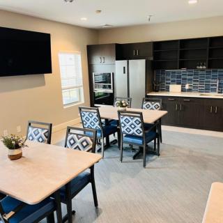 A modern kitchen and dining area with tables, chairs, and a television.