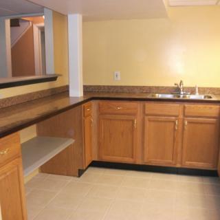 A bar area with wooden cabinets and a countertop sink.