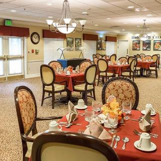 An elegantly set dining room with multiple tables and chairs, ready for guests.