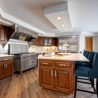 A modern kitchen with wood cabinets, a large island, and stainless steel appliances.