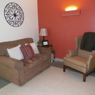 A cozy living room setup featuring a comfortable sofa, an armchair, decorative wall art, and warm lighting.