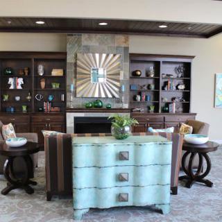 A stylish living room with a modern decor, featuring a central fireplace, decorative shelves, and elegant furniture.