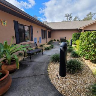 A peaceful courtyard with a pathway, surrounded by lush greenery and outdoor seating.