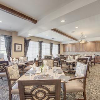 An elegant dining area with neatly arranged tables and chairs, featuring ambient lighting.