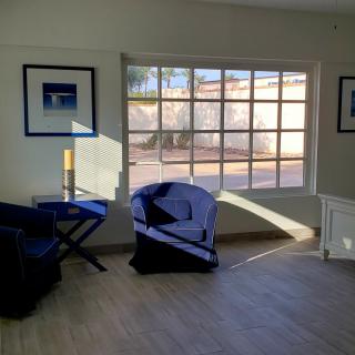 A cozy living room with chairs and sunlight streaming through a large window.