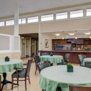 A cozy dining area with round tables covered in green tablecloths and neatly arranged chairs.