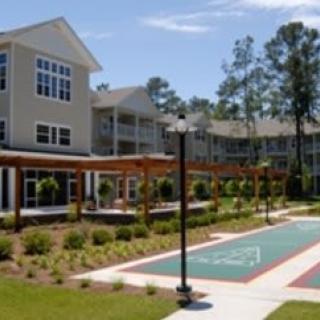 A modern apartment complex featuring a landscaped outdoor recreation area and sunny weather.