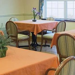 A cozy dining area with tables covered in orange tablecloths and wooden chairs.
