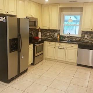 A modern kitchen with stainless steel appliances and tiled flooring.