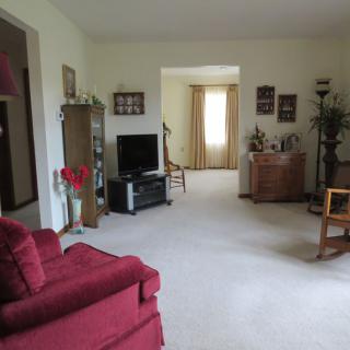 A cozy living room with a TV, red sofa, and various pieces of furniture and decorations.