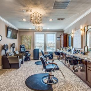 A modern salon interior featuring styling chairs, mirrors, and hair dryers with elegant lighting.