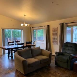 A cozy living and dining area with a sofa, armchair, and dining table set near large windows.