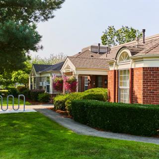 A charming residential area with brick buildings, manicured bushes, and a well-maintained pathway on a sunny day.