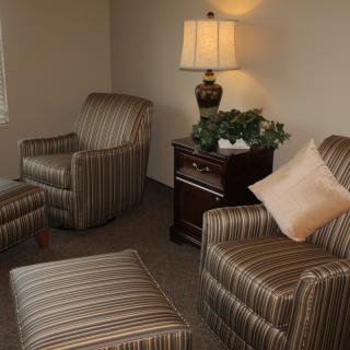 A cozy living room setting with striped armchairs, a side table, and a lamp.