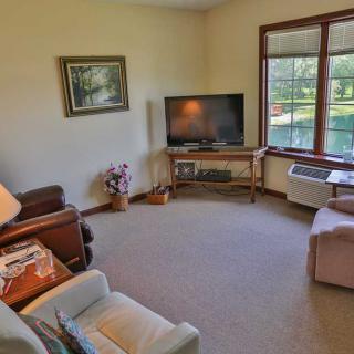 A cozy living room with a television, comfortable seating, and a large window offering natural light.
