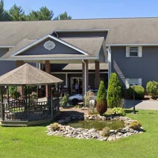 A picturesque building with a gazebo and pond surrounded by well-maintained landscaping on a sunny day.