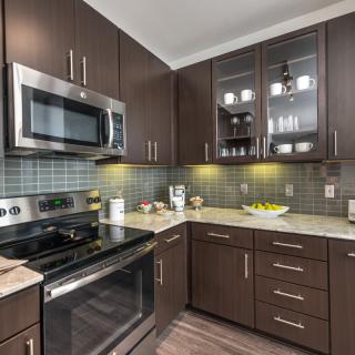 A modern kitchen with dark wood cabinets and stainless steel appliances.