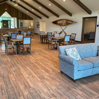 A modern lounge area with wooden floors, featuring dining tables and a comfortable couch.