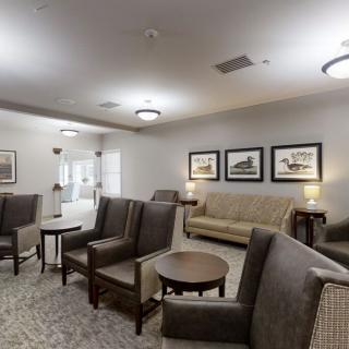 A comfortable lounge area with sofas, chairs, and coffee tables surrounded by artwork on the walls.