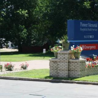 A hospital entrance sign surrounded by greenery and flowers.