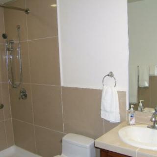 A modern bathroom with a shower, sink, and toilet.
