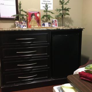 A decorated dresser with framed photos and small plants on top.